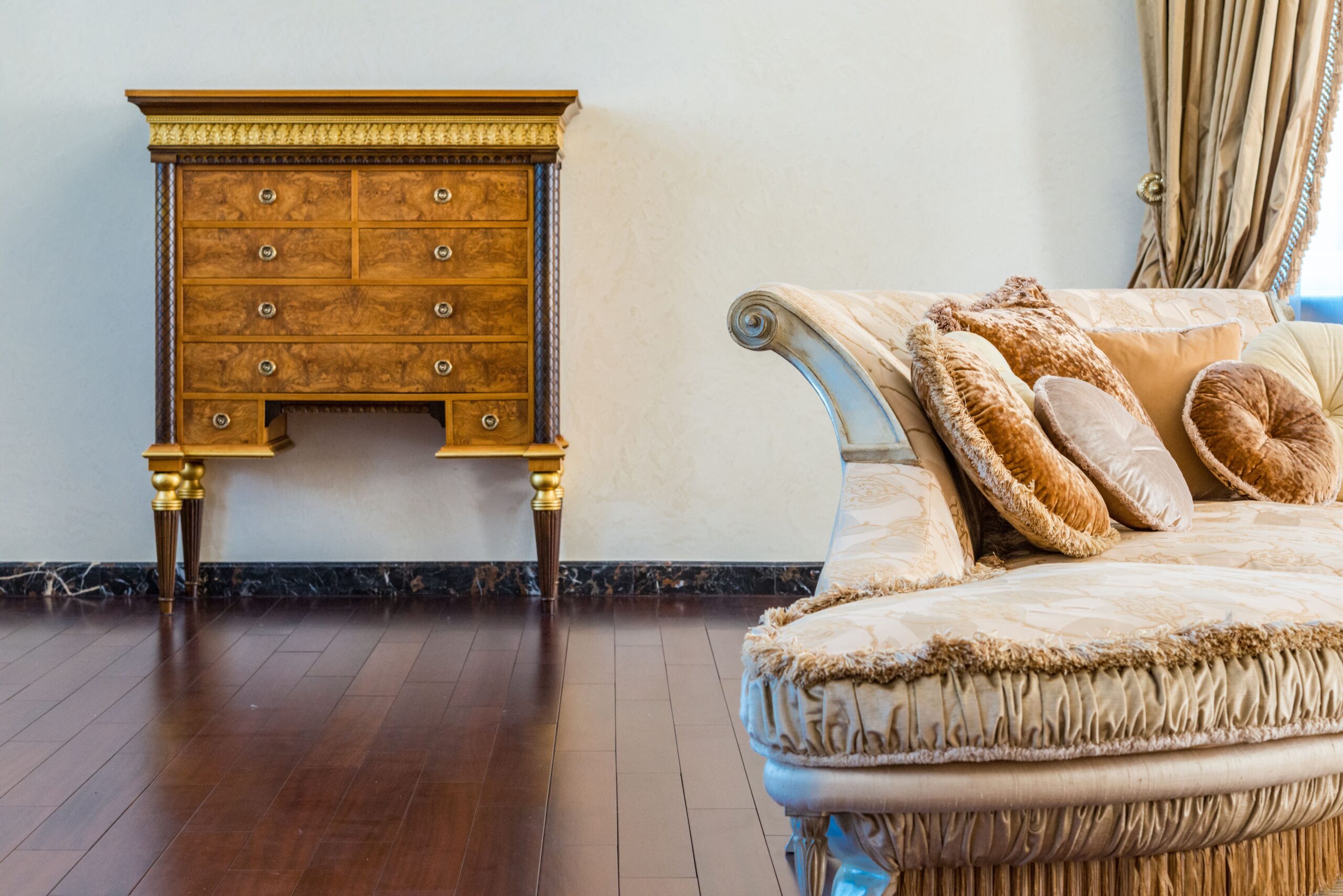 Luxury carved wood chest of drawers beside a cream upholstered sofa in a traditional living room